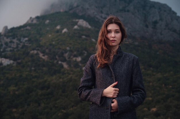 Aziatische vrouw in een grijze jas genietend van het uitzicht in de bergen