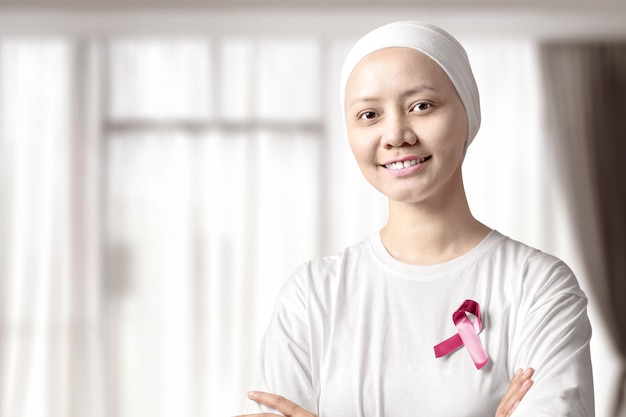 Aziatische vrouw in een wit shirt met een roze lint op het huis