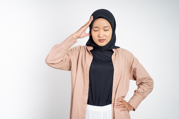 Aziatische vrouw in hijab die haar hoofd vasthoudt met hoofdpijn op een geïsoleerde achtergrond