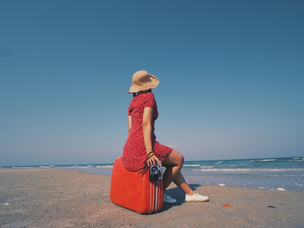 Aziatische vrouw in rode kleding op de toon van de strand uitstekende kleur