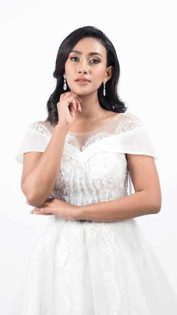 Aziatische vrouw in witte trouwjurk Thaise bruid poseert voor de trouwdag Een jonge vrouw is gelukkig in een trouwjurk Portret shot witte achtergrond in studio Huwelijksjurk voor huwelijksceremonie