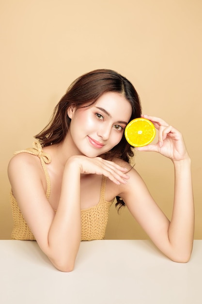 Aziatische vrouw is blij met een perfecte schone, gezonde huid en mooi lang bruin haar met oranje