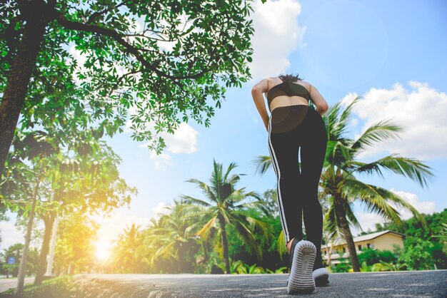 Aziatische vrouw jogt in het park op een zonnige dag vanuit een laag anglefill len flare-effect