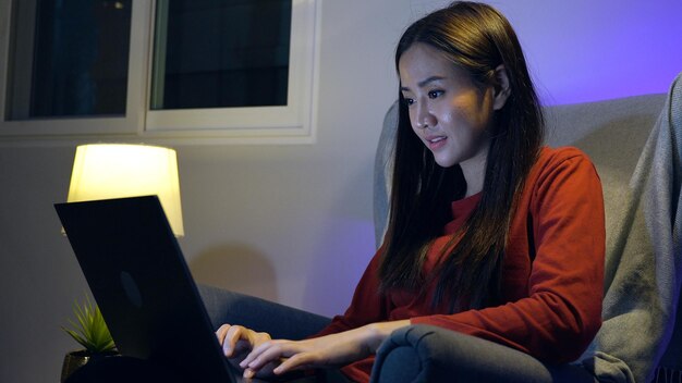 Aziatische vrouw kijken naar film op laptop 's nachts thuis. Ontspannen en recreatie levensstijl.