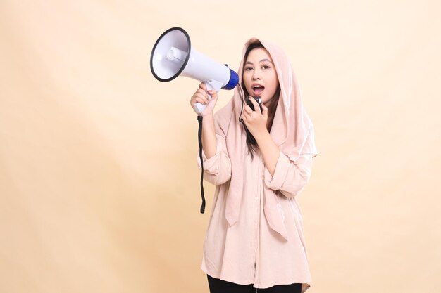 Aziatische vrouw kijkt naar de camera met haar rechterhand die audio vasthoudt en een megafoon luidspreker vasthoudt