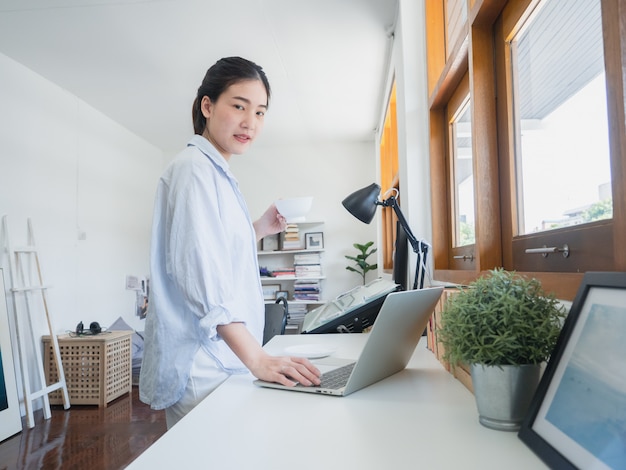 Aziatische vrouw koffie drinken in de werk kamer