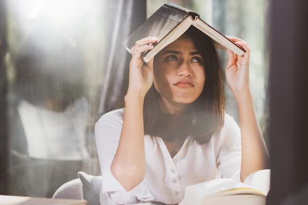 Aziatische vrouw leesboek en werken met saai.