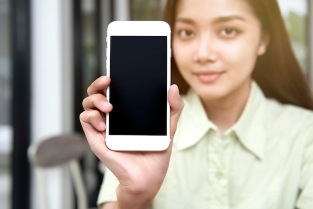 Aziatische vrouw liet haar een scherm van een mobiele telefoon zien in de coffeeshop. Leeg scherm voor kopieerruimte