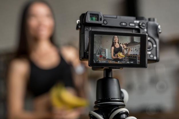 Aziatische vrouw maakt video voor haar blog over gezond eten met behulp van een op een statief gemonteerde digitale camera