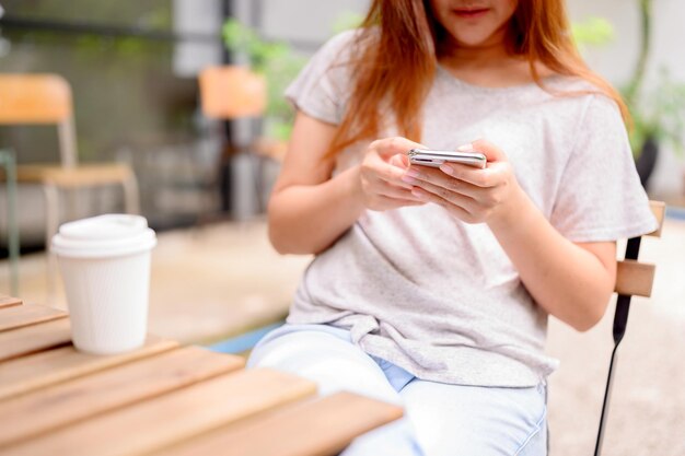 Aziatische vrouw met alleen mobiele telefoon en koffie. Ontspan en recreatie in botanische tuin op vakantie.