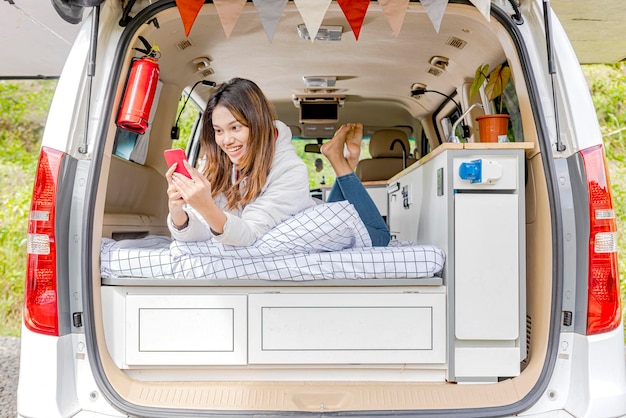 Aziatische vrouw met behulp van mobiele telefoon in de camper