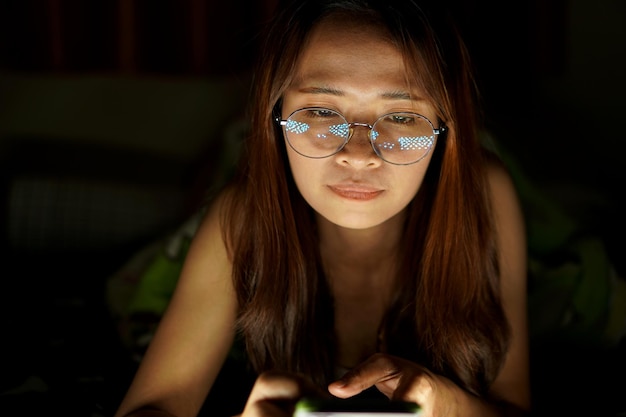 Aziatische vrouw met bril Om de computer bij weinig licht te bekijken, bekijk films online