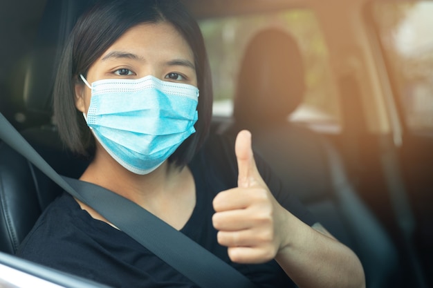 Aziatische vrouw met een masker in een auto Masker om coronavirus te voorkomen, chauffeurs in de straten van de stad tijdens de uitbraak van COVID-19