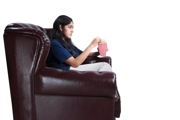 Aziatische vrouw met een popcorn zittend op de bank