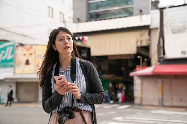 Aziatische vrouw met een telefoon. Bezienswaardigheden in Osaka.