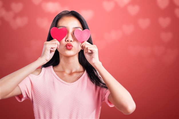 Aziatische vrouw met het rode hart met een gekleurde muur. Valentijnsdag