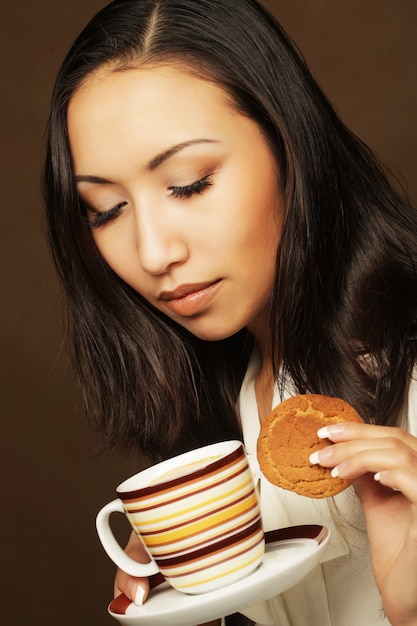 Aziatische vrouw met koffie en koekjes.