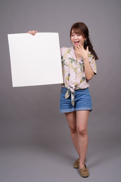 Aziatische vrouw met leeg wit bord met copyspace