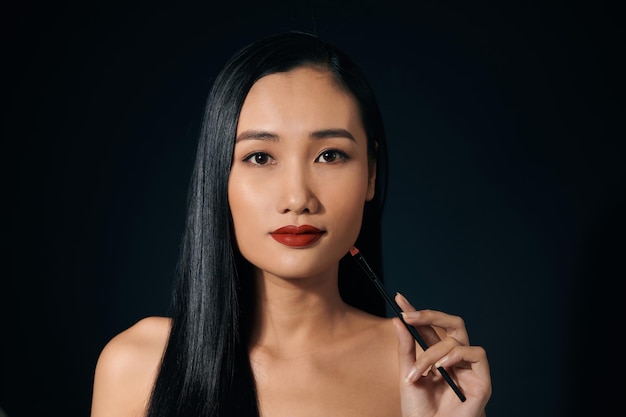 Aziatische vrouw met lippenstift over zwarte achtergrond