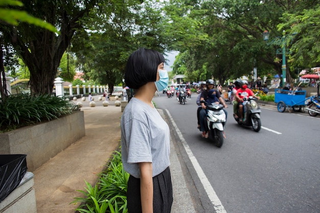 Aziatische vrouw met medisch masker die de weg oversteekt