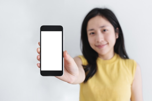 Foto aziatische vrouw met mobiele slimme telefoon met lachend gezicht, leeg wit scherm