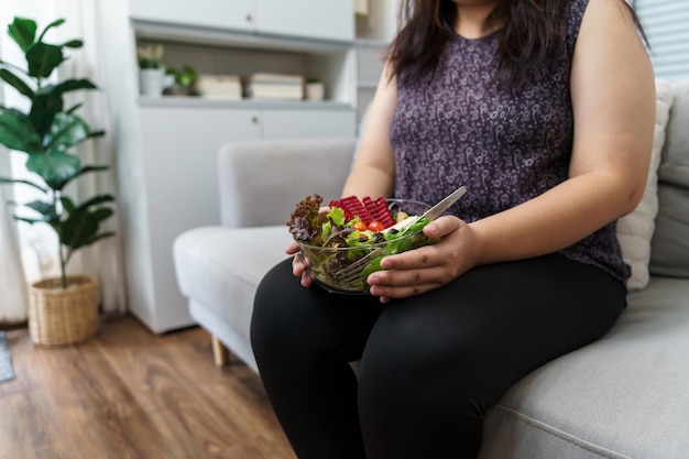 Aziatische vrouw met overgewicht op dieet Gewichtsverlies eten van verse frisse zelfgemaakte salade gezond eten concept Obese vrouw met gewicht dieet levensstijl