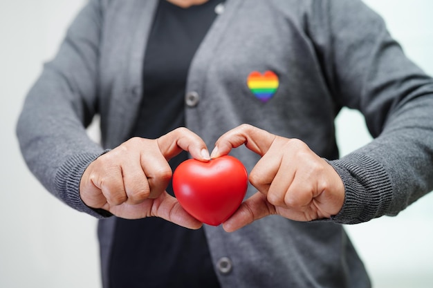 Aziatische vrouw met rood hart met regenboogvlag LGBT-symboolrechten en gendergelijkheid LGBT Pride Month in juni