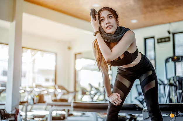 Aziatische vrouw moe na het sporten veegt het zweet op het gezicht af in de fitness gym sportclub in de ochtendFitness gym training en gezonde levensstijl concepten