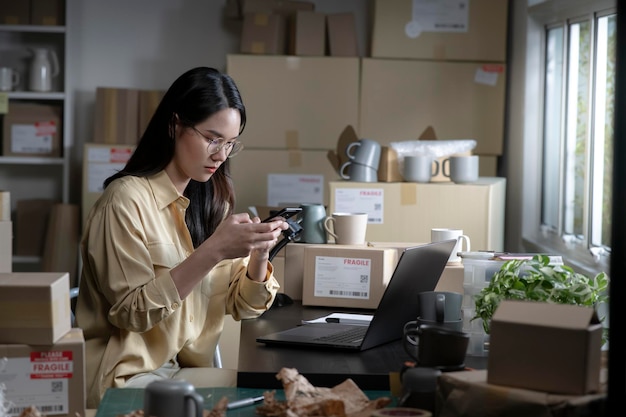 Aziatische vrouw online verkoper bevestigt bestellingen van klant aan de telefoon E-commerce ondernemer kijkt en praat aan de telefoon in winkelmagazijn