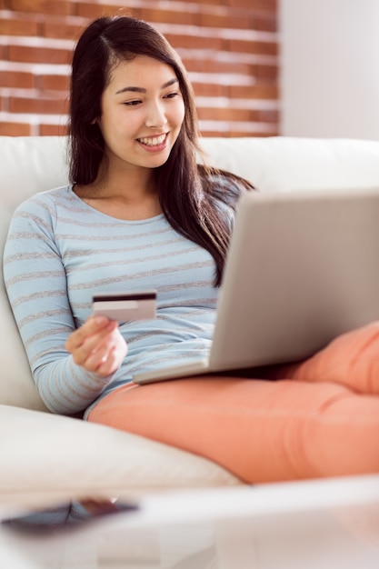 Aziatische vrouw op de laag die laptop met behulp van