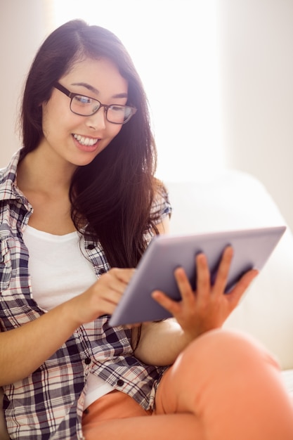 Aziatische vrouw op de laag die tablet gebruikt