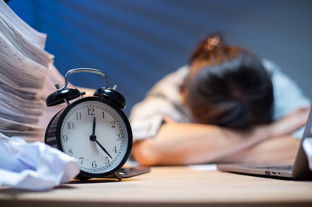 Aziatische vrouw overwerkt en slaapt op de tafel nadat ze zich erg moeilijk voelt. Depressie en angst. Chinees kantoormeisje dat daarna slaapt, kan geen gegevens en oplossing vinden om haar rapport te doen. Workaholic-mensen.