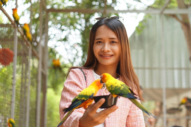 Aziatische vrouw papegaaien voeden in de tuin