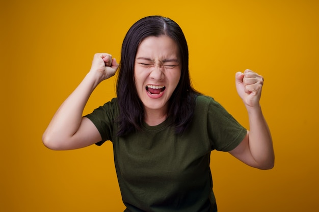 Aziatische vrouw permanent en boos geïsoleerd over gele muur.