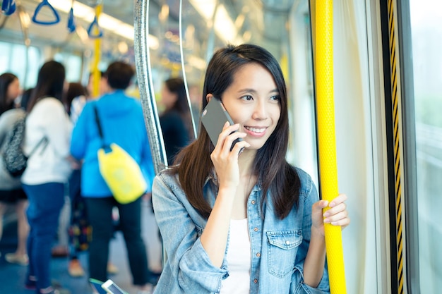 Aziatische vrouw praat met mobiele telefoon in trein