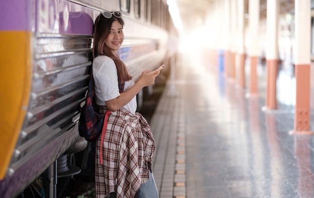 Aziatische vrouw Reiziger die geluk voelt voordat hij gaat reizen op het treinstation, reis- en levensstijlconcept