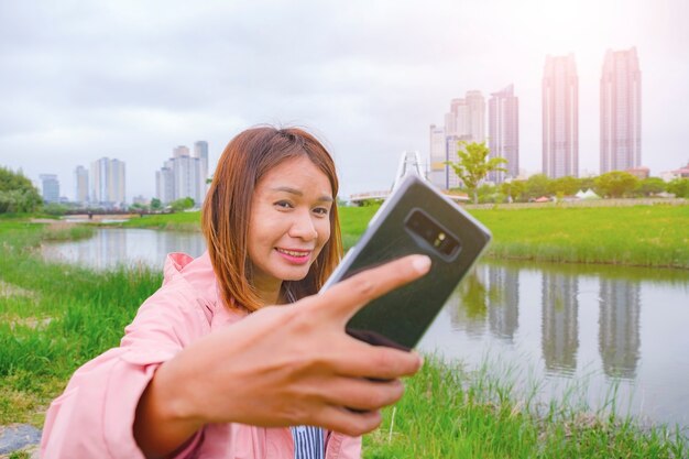 Aziatische vrouw selfie met smartphone in taehwagang grand park in ulsan korea in april.