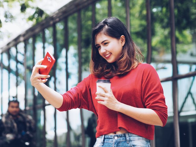 Aziatische vrouw selfie zichzelf en koffiekopje in de hand te houden.