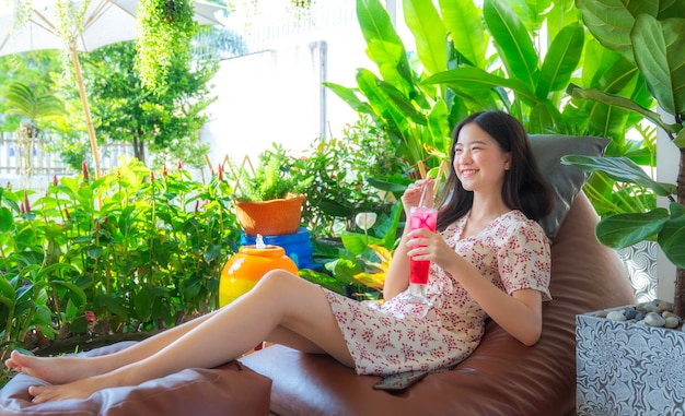 Aziatische vrouw slaapt en ontspant met een rode drank bij de hand in haar tuin thuis Groene natuur in het resort