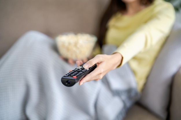 Foto aziatische vrouw smart tv kijken en afstandsbediening gebruiken hand met televisie-audio-afstandsbediening thuis met de afstandsbediening televisie
