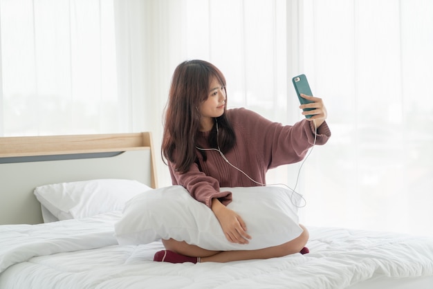 Aziatische vrouw smartphone spelen op bed