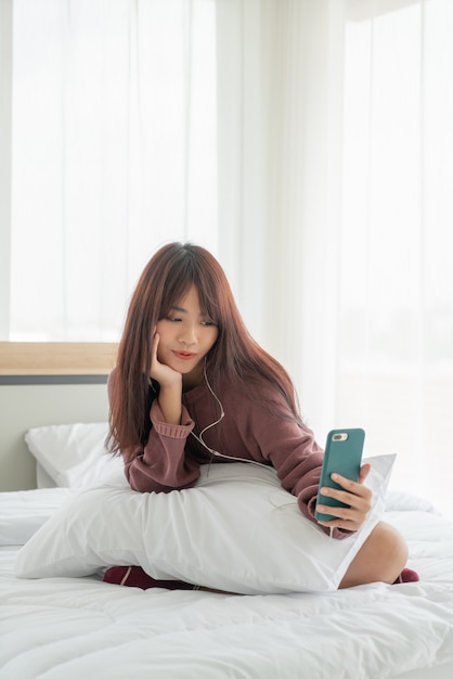 Aziatische vrouw smartphone spelen op bed