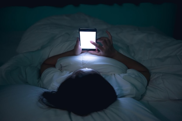 Aziatische vrouw speelspel op smartphone in het bed 's nachts thailand peopleaddict social media