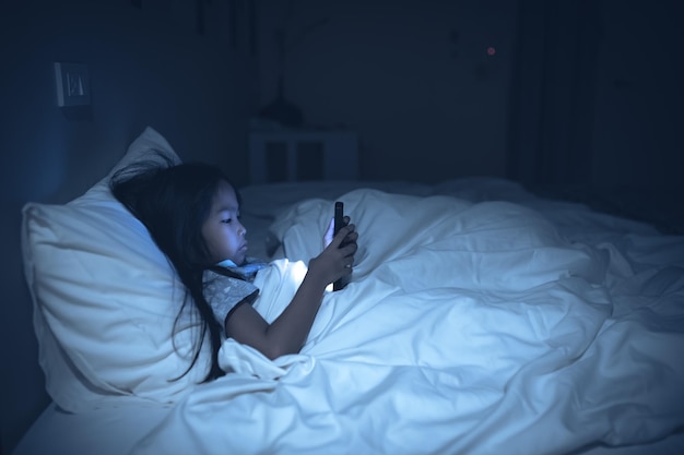 Aziatische vrouw speelspel op smartphone in het bed 's nachts Thailand peopleAddict social media