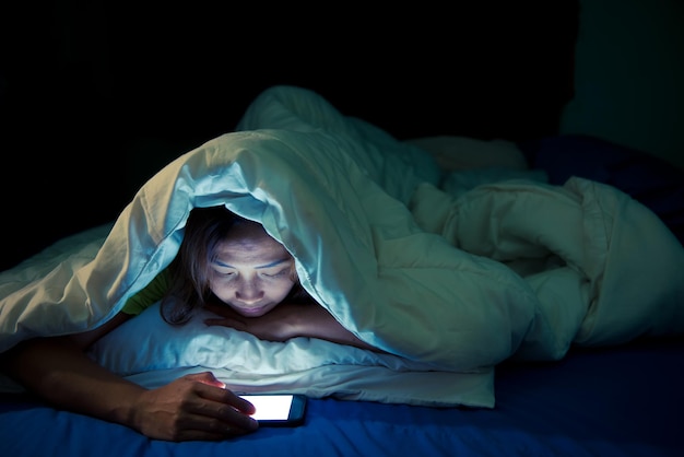 Aziatische vrouw speelt 's nachts smartphone in bed Thailand mensen Verslaafde sociale media Speel de hele nacht internet