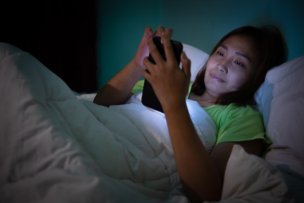 Aziatische vrouw speelt 's nachts smartphone in bed Thailand mensen Verslaafde sociale media Speel de hele nacht internet
