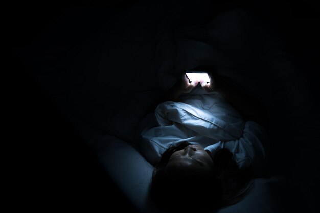 Aziatische vrouw speelt smartphone 's nachts in bed Thailand mensen