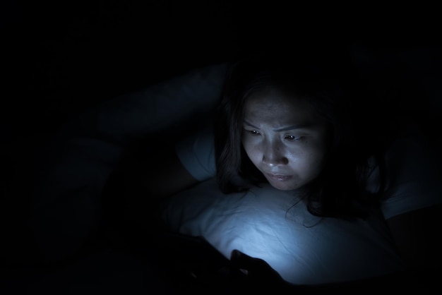 Aziatische vrouw speelt smartphone 's nachts in bed Thailand mensen