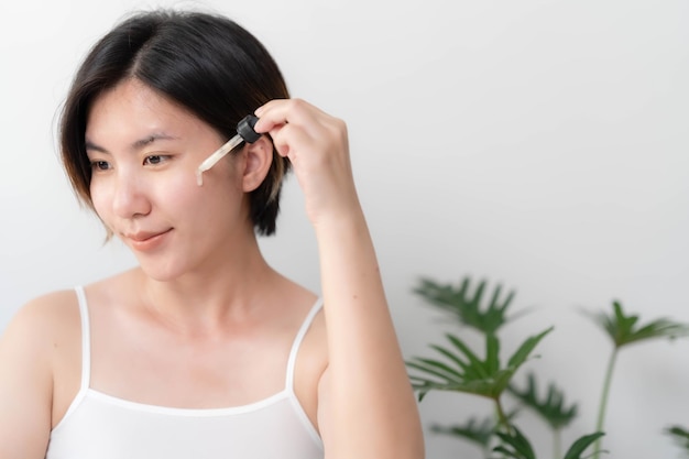 Aziatische vrouw stopt huidserums voor haar gezicht om de huid zacht, gehydrateerd wit en helder te maken