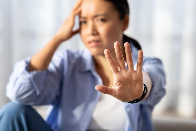 Foto aziatische vrouw toont stop gebaar thuis interieur